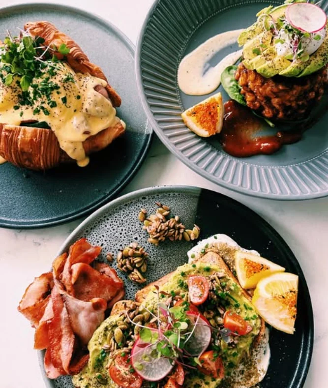 A spread of brunch plates at PointBreak Cafe — eggs benny croissant, smashed avo and bacon, beachfront in Coolangatta on the Gold Coast